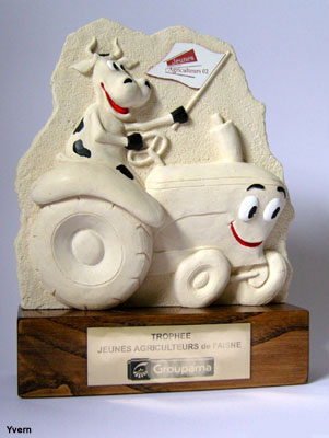 Trophée présentant en bas relief une vache montée sur un tracteur et tent un drapeau d'un syndicat agricole